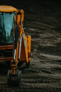 Close-up of a yellow excavator on a construction site with muddy terrain.